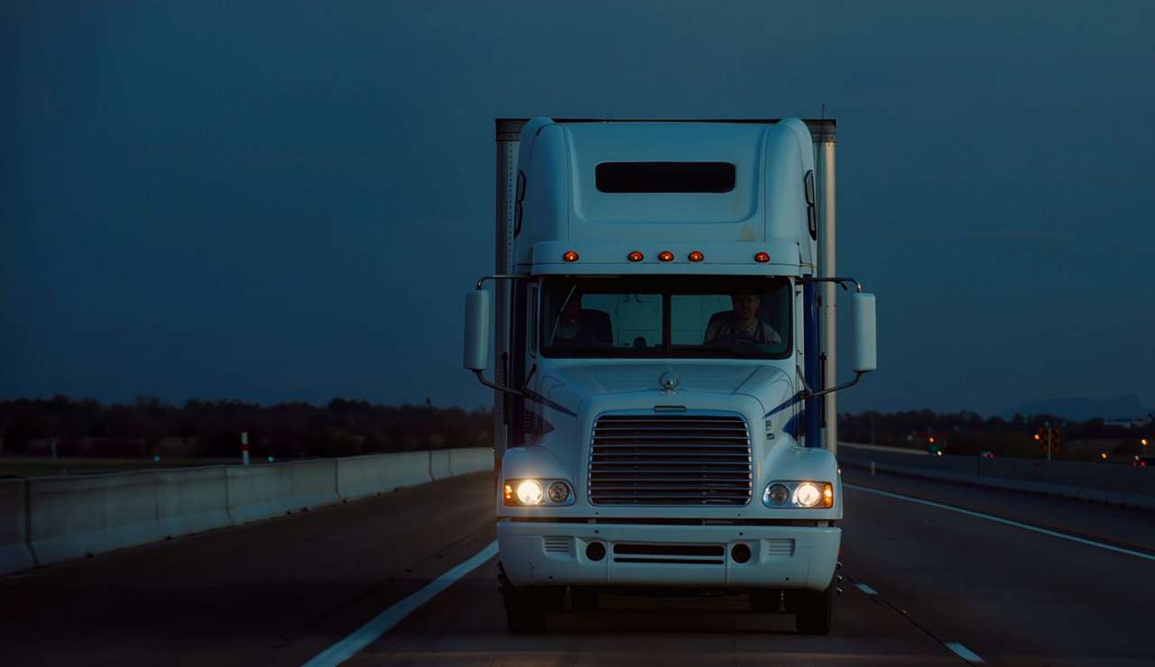Semi truck with a dry van trailer on a highway at dusk